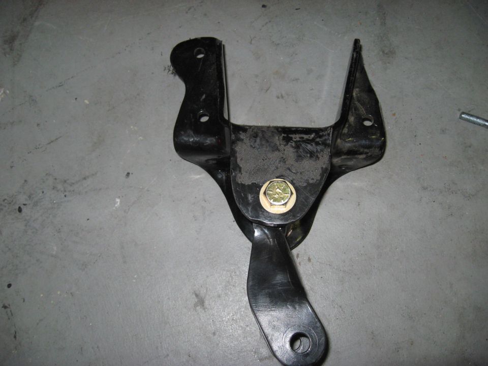 Black metal bracket with bolt and washer on concrete floor.