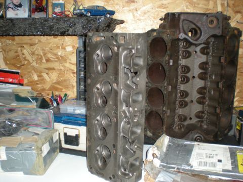 1974 Ford Ranchero - Two cast iron engine cylinder heads are displayed in a workshop setting. The head on the left is clean and bare, while the head on the righ…