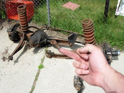 1996 Ford Bronco - A rusty rear axle assembly with coil springs and brake components is laid out on a concrete surface. A person's hand is visible in the fore…