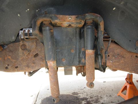 1996 Ford Bronco - The underside of a heavily rusted 1996 Ford Bronco shows the rear suspension system with two shock absorbers and leaf springs. The vehicle…