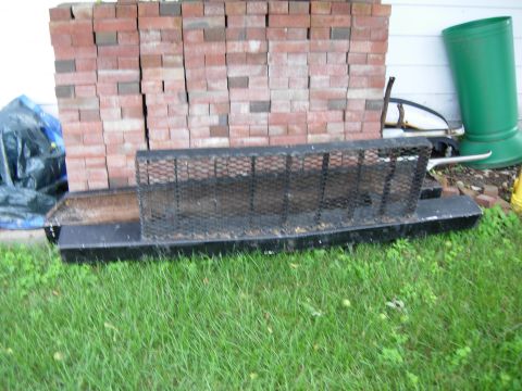 1996 Ford Bronco - A black metal grate sits on top of a black metal trough in front of a stack of bricks. A blue tarp is visible to the left, and a green down…