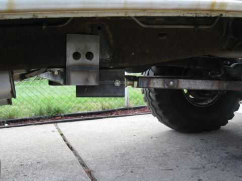 1996 Ford Bronco - Custom metal brackets and a tubular control arm are bolted to the frame of a vehicle, connecting to the suspension near the rear tire. The…