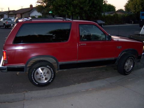 1991 Ford Bronco - Side view of a red SUV parked outdoors.