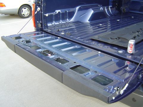 2008 Ford F-250 - The bed of a blue 2008 Ford F-250 pickup truck is shown with the tailgate lowered, revealing the bedliner and a can of soda.