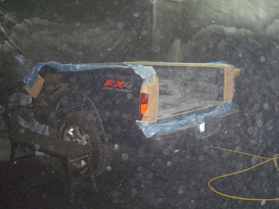 Black truck bed with FX4 OFF ROAD decal, taped and covered with plastic sheeting