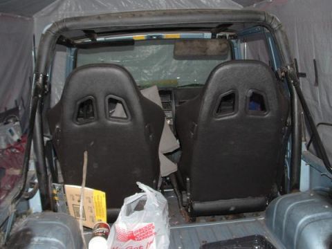 2001 Ford F-350 - The interior of a vehicle is shown, two black racing seats and a roll cage, with some items in the background.
