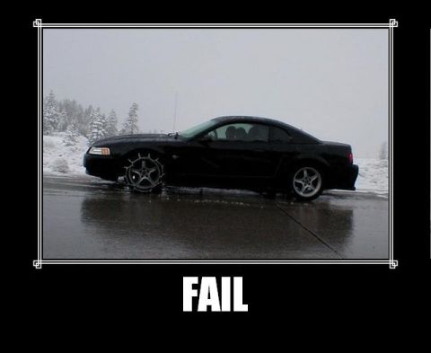 1988 Mercury Grand Marquis - A black coupe is stuck on a wet road with snow chains on its front wheel during winter.