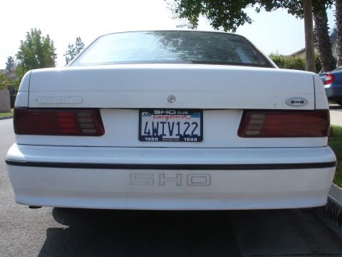 1990 Ford Taurus - Rear view of a white Ford Taurus SHO, a SHO Club license plate frame and 'SHO' badging on the bumper.