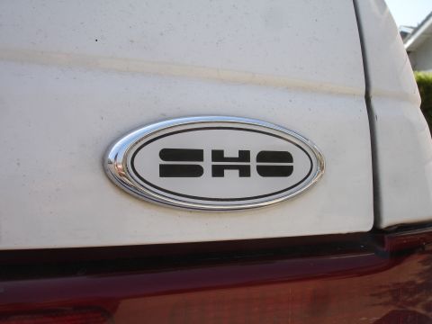1990 Ford Taurus - Close-up of the SHO badge on the rear of a white vehicle.