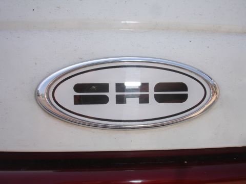 1990 Ford Taurus - Close-up of an oval SHO badge on a vehicle's exterior.