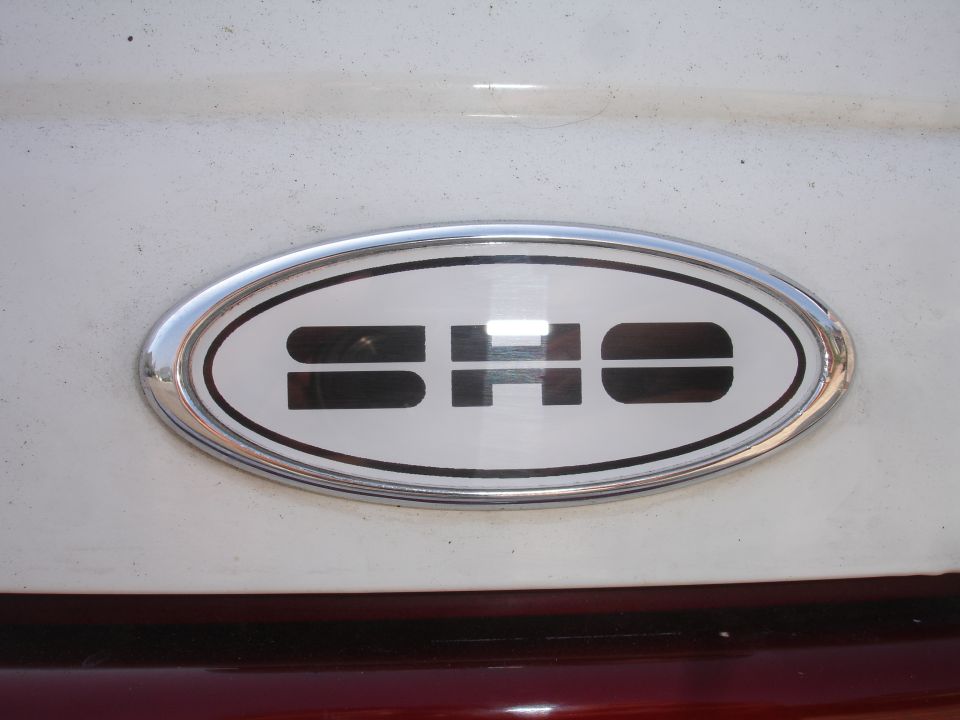 Oval SHO badge on white car body with chrome trim