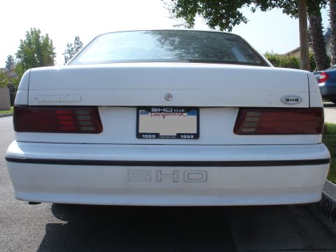 1990 Ford Taurus - This white Ford Taurus SHO features a rear badge and a license plate frame indicating 1989 and 1999.