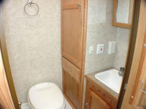 2005 Chevrolet C-6500/Kodiak - Interior view of an RV bathroom, showing a toilet, sink, and storage cabinets.