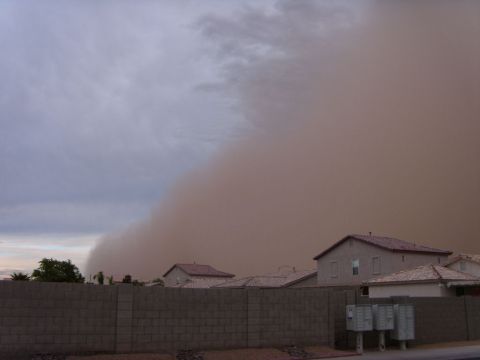 1978 Ford Bronco - A towering brown dust storm wall rolls over a Southwest desert subdivision, swallowing the sky above tile-roofed stucco houses. A gray bloc…