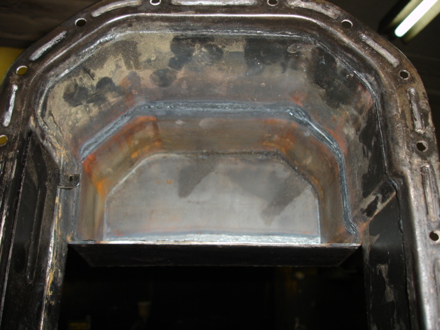 Close-up of a metal oil pan with visible welds and some rust