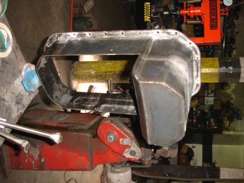 1980 Ford Bronco - A metal oil pan is shown on a piece of shop equipment, likely for repair or modification.