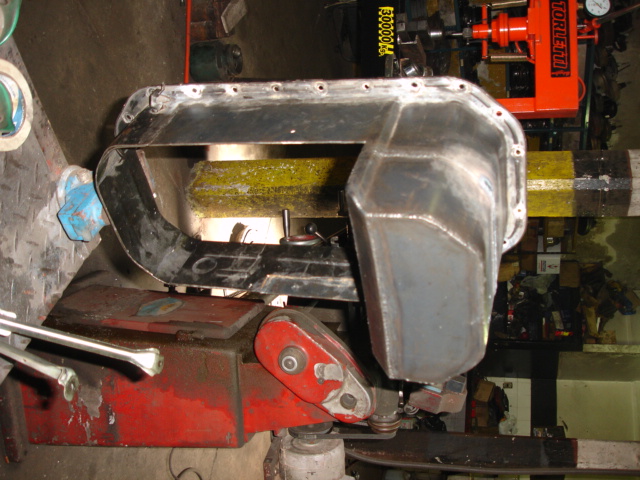 metal oil pan on a red and black machine in a garage