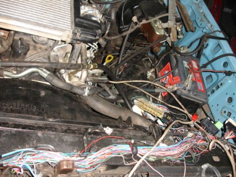 1980 Ford Bronco - The engine bay shows a complex wiring harness and a battery, with no clear year identification.