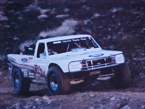 1984 Ford Bronco - This modified Ford truck, likely from the late 1980s, competes in an off-road race.