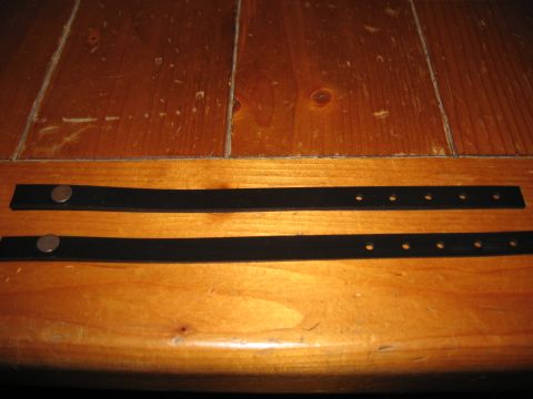 1968 Shelby GT500 - Two black straps, each with a metal snap and multiple holes, lie on a wooden table.