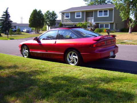 1995 Ford Probe - A red 1995 Ford Probe is parked on the side of a suburban street, its sporty design with a prominent rear spoiler.