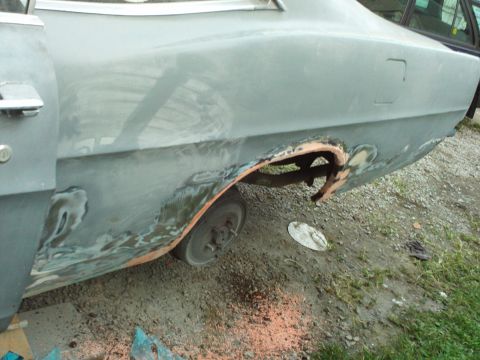 1967 Ford Galaxie - The rear wheel well area of a car is undergoing repair, with visible rust and bodywork in progress.