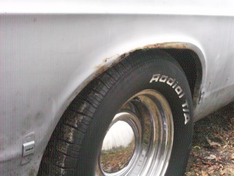 1967 Ford Galaxie - The rear wheel well of a vehicle shows signs of rust around the fender opening and a Radial T/A tire.