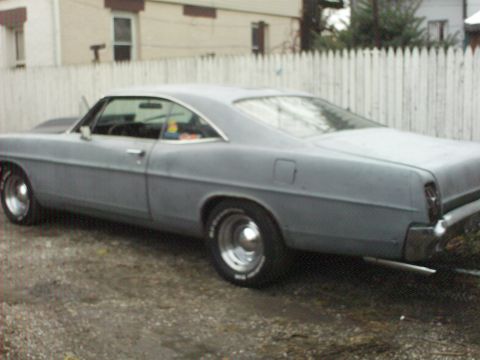 1967 Ford Galaxie - A 1967 Ford Galaxie coupe in primer is parked outdoors, viewed from the rear three-quarter angle.