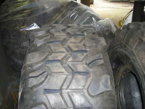 1979 Ford Bronco - A close-up view of two large, off-road tires with aggressive tread patterns. The tire in the foreground is angled towards the camera, while…