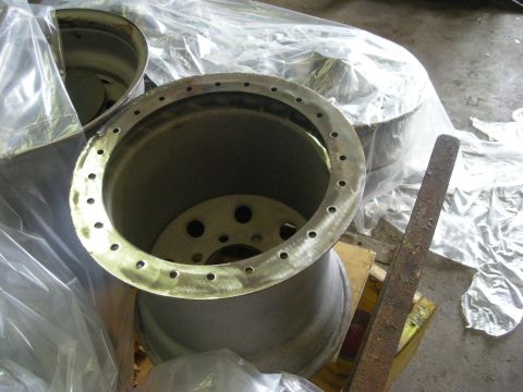 1979 Ford Bronco - Two unfinished wheel rims are shown, one in the foreground with a ring of holes around its edge. The rims appear to be for a truck or SUV a…