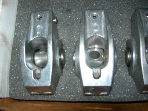 1984 Ford Bronco - Two aluminum rocker arms with the number "5" stamped on them are shown in close-up, resting on a gray speckled foam surface.