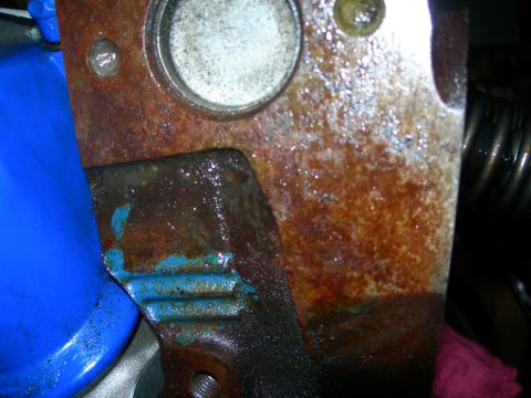 1984 Ford Bronco - A close-up view of a heavily rusted engine block with a blue oil filter attached. The engine appears to be part of a 1984 Ford Bronco build.
