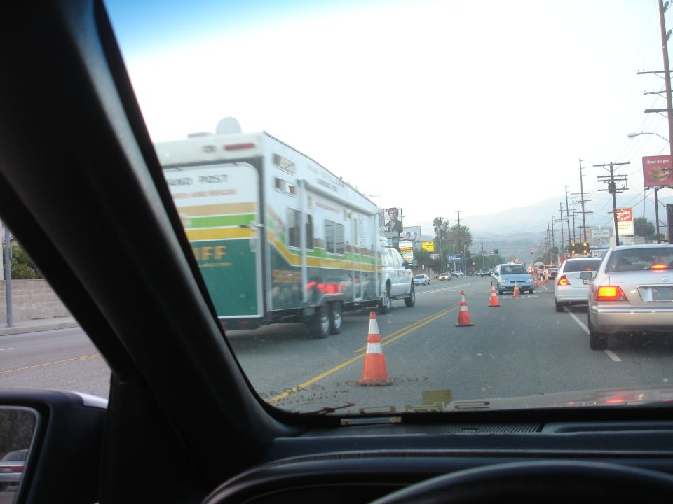 Sheriff trailer being towed in traffic on a street.