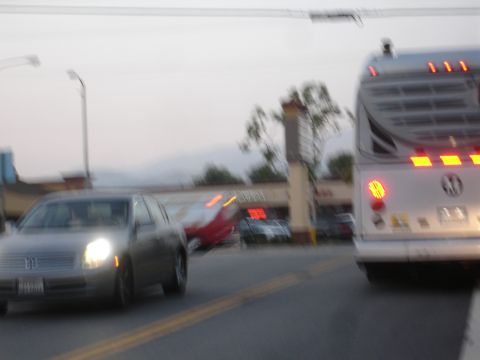 1993 Ford Taurus - A silver sedan drives down a street with a bus in the background.