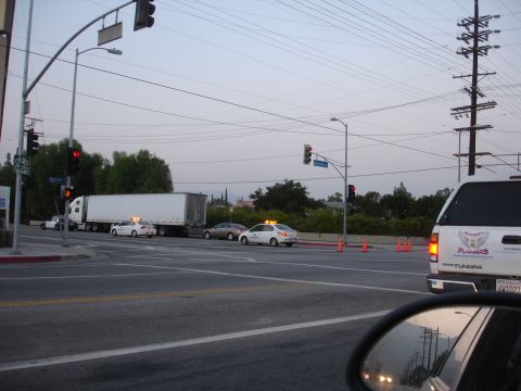 1993 Ford Taurus - Traffic moves through an intersection with a semi-truck and several sedans, under a network of power lines.