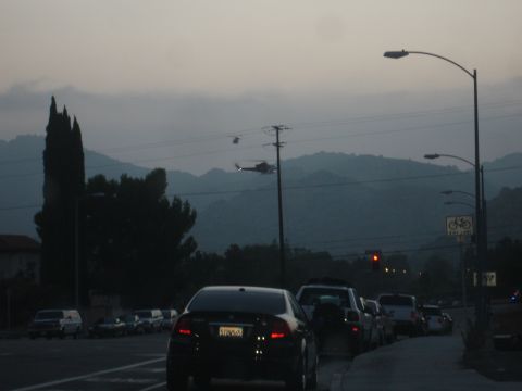 1993 Ford Taurus - Traffic moves slowly on a road at dusk with two helicopters visible in the sky.