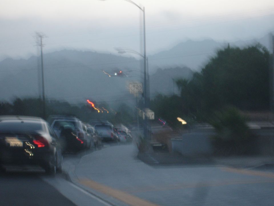 Traffic scene with cars on a road at dusk, mountains in background