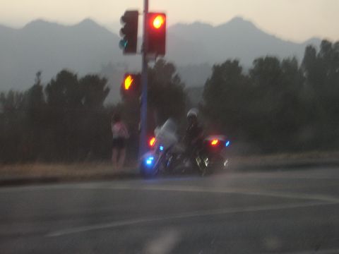 1993 Ford Taurus - A police motorcycle is stopped at a traffic light with its emergency lights activated.