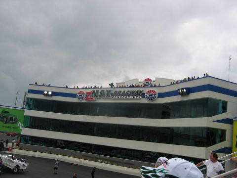 1992 Ford Mustang - The ZMax Dragway building at Concord, USA, under a cloudy sky with spectators on the roof.