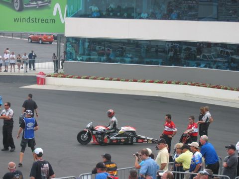1992 Ford Mustang - A drag motorcycle and rider are on the track, with spectators in the background.