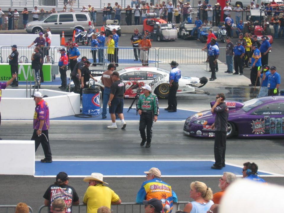 Drag racing cars on track with spectators in background