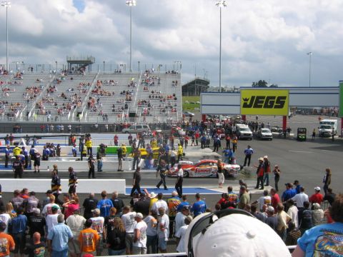 1992 Ford Mustang - NHRA Carolina Nationals event with spectators in the stands and a dragster on the track.