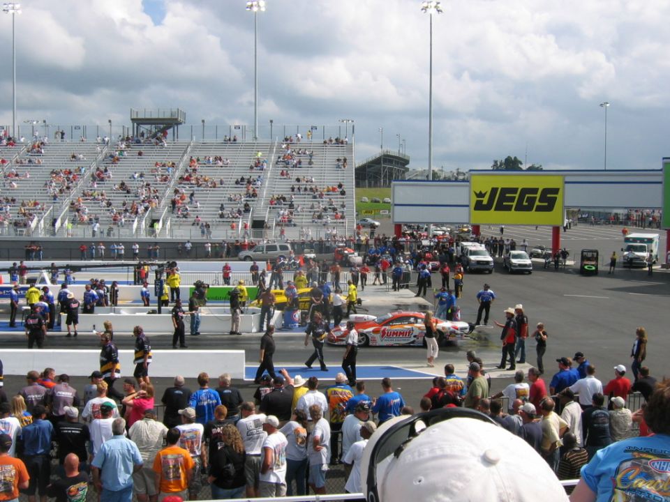 Drag racing track with grandstands full of spectators and a race car on the track