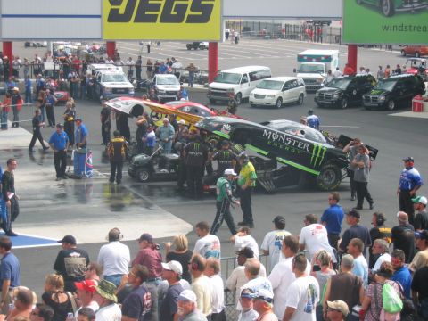 1992 Ford Mustang - A pit area at a drag racing event with multiple cars and crew members preparing for a race.