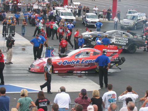 1992 Ford Mustang - NHRA Carolina Nationals event with multiple dragsters and support vehicles on the track.