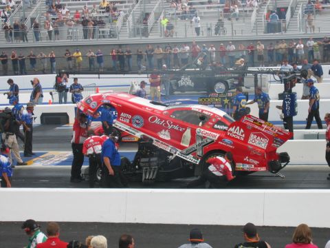 1992 Ford Mustang - A red drag car with "Old Spice" livery is being worked on by a crew, with spectators in the background.