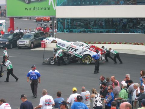 1992 Ford Mustang - Crew members push a drag racing car on the track during an event.