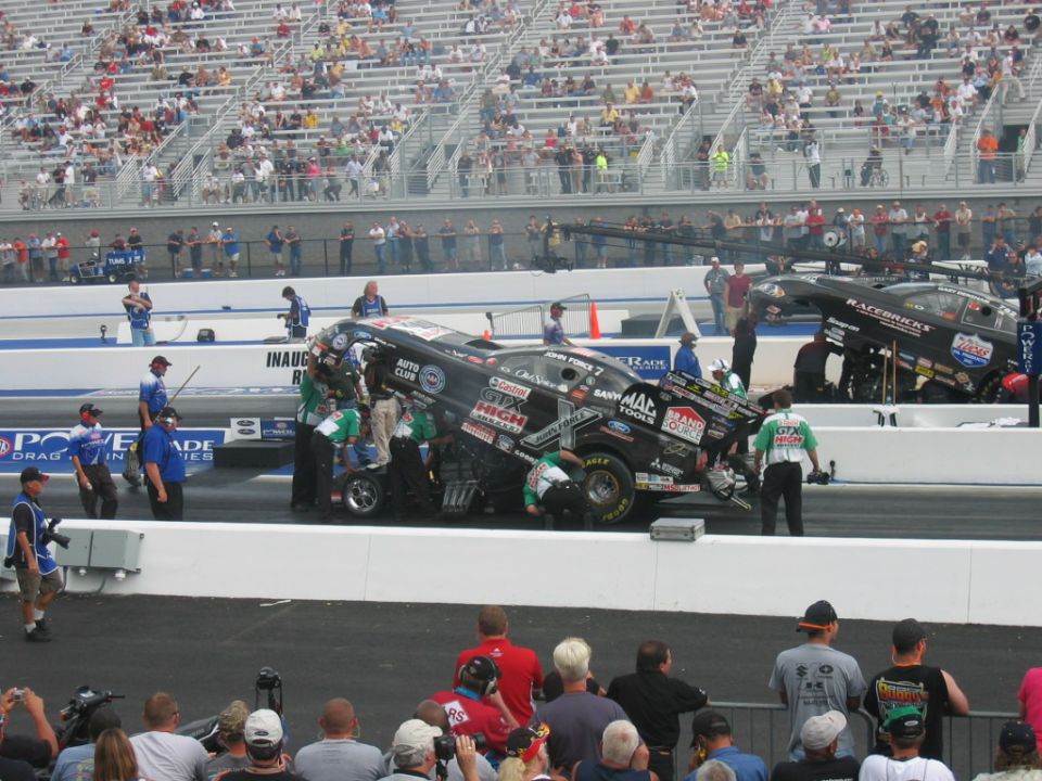 Drag racing cars with crews working on them at a track