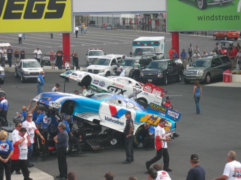 1992 Ford Mustang - Crew members service two drag racing cars at an event, with spectators and support vehicles present.