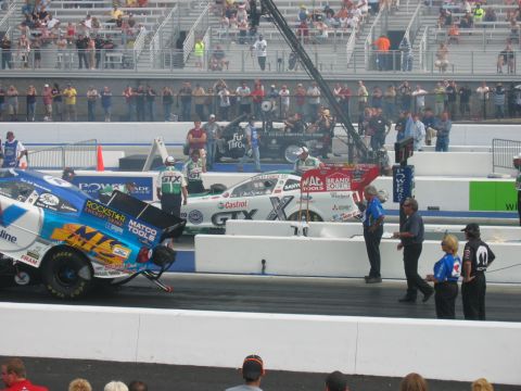 1992 Ford Mustang - Drag racing cars prepare for a run at a NHRA event, with spectators watching from the stands.